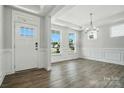 Bright entryway with hardwood floors, modern chandelier, and wainscoting along the walls at 2012 Embassy Ct # 46, Charlotte, NC 28213