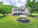 Inviting exterior featuring a welcoming front porch, well-manicured lawn, and lush greenery at 206 Montclair Dr, Locust, NC 28097