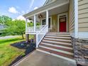 Cozy front porch with decorative plants, a 'Welcome' sign, and a charming red door at 206 Montclair Dr, Locust, NC 28097