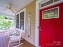 Welcoming front porch with rocking chairs, a ceiling fan, and a vibrant red door at 206 Montclair Dr, Locust, NC 28097