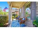 Inviting porch with brick columns and wicker chairs on a blue patterned rug and colorful flowers at 2119 Augusta National Dr, Denver, NC 28037