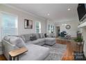 Spacious living room featuring a comfortable gray sectional, hardwood floors, and an open layout leading to the dining area at 2124 Roslyn Ave, Charlotte, NC 28208