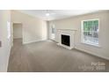 Sunlit living room featuring a cozy fireplace, neutral decor, and a door leading to the outside at 2512 Captains Watch Ne Rd, Kannapolis, NC 28083