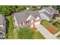 An aerial view of a brick two-story home with red shutters, a well-manicured lawn, and a two-car garage at 3005 Sandbox Cir, Indian Trail, NC 28079