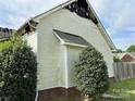 Side view of a fire-damaged one-story home with white siding and brick foundation at 3205 Creek Trail Rd, Indian Trail, NC 28079