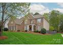 Stunning brick home featuring a lush lawn, mature trees, and manicured landscaping at 4027 Wallbrook Dr, Matthews, NC 28105