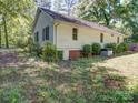 The backyard showcases the home's exterior, bordered with green shrubs and a grassy lawn at 610 N Pine Ln, Wadesboro, NC 28170