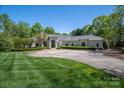 Stately home with circular driveway, lush lawn, and manicured landscaping creating a grand entrance at 7912 Baltusrol Ln, Charlotte, NC 28210