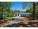 Stately home features a circular driveway and mature landscaping, creating a welcoming and private setting at 7912 Baltusrol Ln, Charlotte, NC 28210