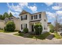 This two-story home with attached garage features neutral siding, black shutters and landscaped front yard at 8424 Spirea Ct, Charlotte, NC 28215