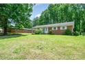 Traditional brick home featuring a well-kept lawn, mature trees, and a welcoming front entrance at 907 E 9Th Ave, Gastonia, NC 28054