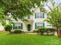Inviting home with green door and shutters, complemented by lush lawn and mature landscaping. For Sale by Canopy2025 at 11719 Withers Mill Dr, Charlotte, NC 28278