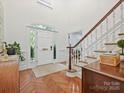 Bright foyer featuring wood floors, staircase, and a white front door with side windows at 2417 Calais Pl, Charlotte, NC 28211