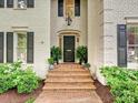 Close-up of a house entrance featuring a black front door, brick steps, and manicured landscaping at 2417 Calais Pl, Charlotte, NC 28211