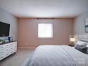 Cozy bedroom with neutral tones, soft carpet, and dresser with a television at 2900 #G Heathstead Pl, Charlotte, NC 28210