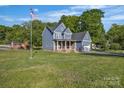 Inviting two-story blue home with brick accents, featuring a spacious lawn and mature trees at 3075 Jamestown Dr, Gastonia, NC 28054