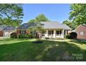 Charming brick home featuring a well-manicured lawn and mature trees at 317 Port Royal Dr, Matthews, NC 28105
