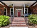 Inviting front porch with brick steps, a porch swing, and beautiful landscaping at 4301 Middle Stream Rd, Charlotte, NC 28213