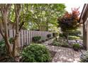 Landscaped backyard featuring a stone walkway, bench, mature trees, and lush plantings at 5128 Dunes Ct, Charlotte, NC 28226