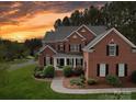 Charming two-story brick home featuring manicured landscaping and inviting front porch at sunset at 914 Olive Mill Ln, Matthews, NC 28104