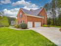View of the brick house highlighting the three-car garage and lush green lawn at 914 Olive Mill Ln, Matthews, NC 28104