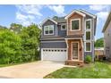 Charming two-story home with a two-car garage, lush landscaping, and a mix of modern siding materials at 933 Tennyson Dr, Charlotte, NC 28208