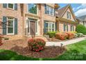 Close-up of home's entrance showcasing brick facade, landscaping, and a well-maintained front walkway and lawn at 10101 Bayart Way, Huntersville, NC 28078
