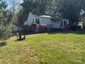 Quaint home with a lush green yard and blooming azaleas, complete with a cozy Adirondack chair at 1059 16Th Nw Ave, Hickory, NC 28601