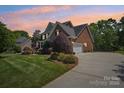Brick home featuring an attached garage, long driveway, and well-maintained lawn at 10716 Persimmon Creek Dr, Mint Hill, NC 28227