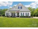 Beautiful home featuring a lush green lawn, an American flag, black shutters, and a welcoming covered front porch at 500 Chicory Cir, Matthews, NC 28104