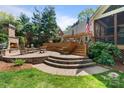 A stone patio with outdoor fireplace with tiered brick seating area and a beautiful green lawn at 6202 Providence Country Club Dr, Charlotte, NC 28277