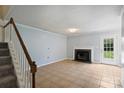 Spacious living room with a fireplace and staircase, featuring tile flooring and neutral walls at 10943 Winterbourne Ct, Charlotte, NC 28277