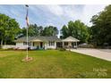 Charming home featuring a lush lawn, inviting porch, carport and an American flag at 1115 Old Thompson Ave, Lancaster, SC 29720