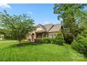 Beautifully landscaped home with lush green lawn, mature trees, and charming stone and brick facade at 11424 Brangus Ln, Mint Hill, NC 28227