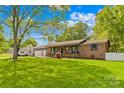 Charming single-story home with beautiful green lawn, shade tree, and neutral exterior with a welcoming front porch at 1279 Rocky Creek Rd, Shelby, NC 28152