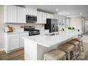 Bright kitchen features stainless appliances, white cabinets, stone countertop and an island with barstool seating at 129 Millstream Dr, China Grove, NC 28023