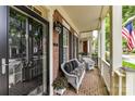 Cozy covered porch with wicker seating, floral cushions, brick flooring, and ample space for relaxing at 172 Harper Lee St, Davidson, NC 28036