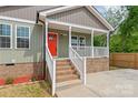 Inviting porch with white railings leads to a vibrant red front door and stylish brick foundation at 320 Evans Nw St, Concord, NC 28027