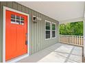 Close-up showcasing the vibrant red front door and charming covered porch with white pillars at 320 Evans Nw St, Concord, NC 28027