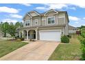 Inviting two-story home with stone accents, a covered front porch, and an attached two-car garage at 341 Pleasant Hill Se Dr, Concord, NC 28025