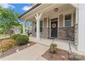 Inviting covered front porch with stone accents, stylish black front door with wreath, and lovely landscaping at 341 Pleasant Hill Se Dr, Concord, NC 28025