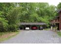 Large carport that can accommodate up to three vehicles, nestled amidst a backdrop of mature trees and lush greenery at 347 Poole Rd, Troy, NC 27371