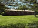 A charming brick home with a metal roof surrounded by a lush, green lawn and mature trees at 370 Sherrill Farm Rd, Lincolnton, NC 28092