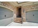 Garage entry featuring brick stairs, iron railing and two car garage with neutral colored doors at 8670 Arbor Oaks Cir, Concord, NC 28027