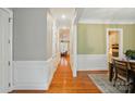 Well-lit hallway with hardwood floors, white wainscoting, and access to multiple rooms, including a view of the kitchen at 9652 Wheatfield Rd, Charlotte, NC 28277