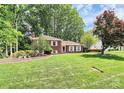 Charming brick home with white shutters, surrounded by mature trees and a spacious front lawn at 1024 Regency Dr, Charlotte, NC 28211