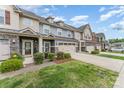 View of townhomes with two-car garages, stone accents, and well-manicured lawns on a sunny day at 11062 Discovery Nw Dr, Concord, NC 28027