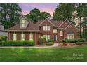 Well maintained brick two-story home featuring manicured lawn and mature trees against a dusky sky at 15535 Eagleview Dr, Charlotte, NC 28278