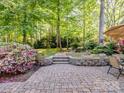 Charming backyard stone patio with a dining set, surrounded by colorful flowers and greenery perfect for outdoor relaxation and entertaining at 166 Wilson Lake Rd, Mooresville, NC 28117