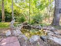 Picturesque backyard pond with a decorative heron statue nestled among the trees and greenery at 166 Wilson Lake Rd, Mooresville, NC 28117